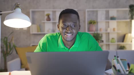 Happy-black-businessman-using-laptop-in-home-office,-completing-work.
